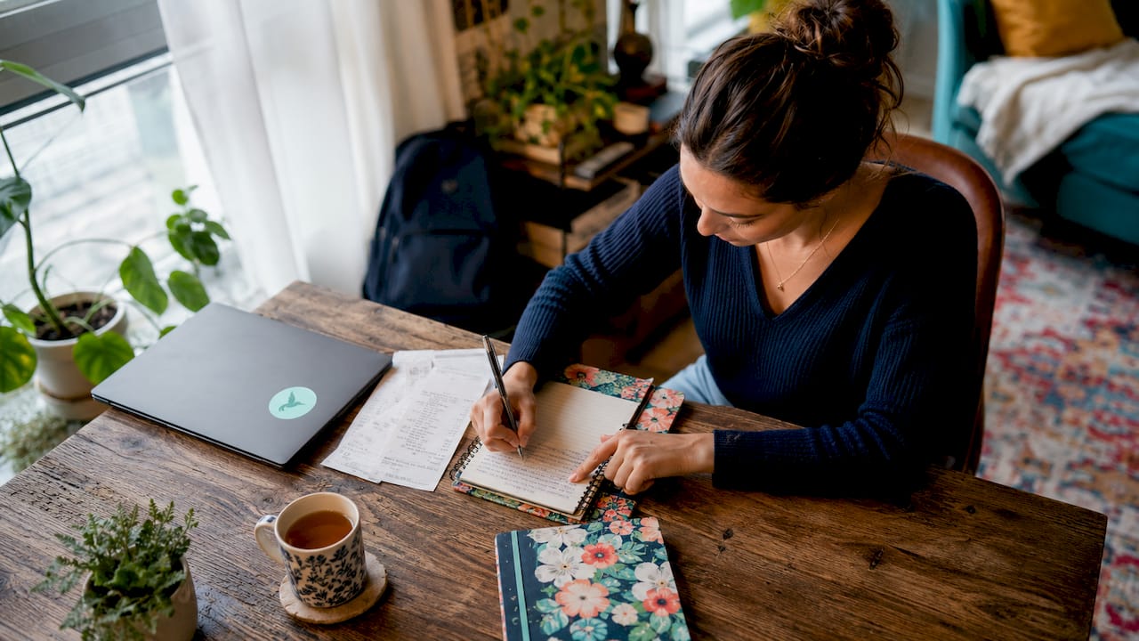 Woman logging daily expenses at home desk