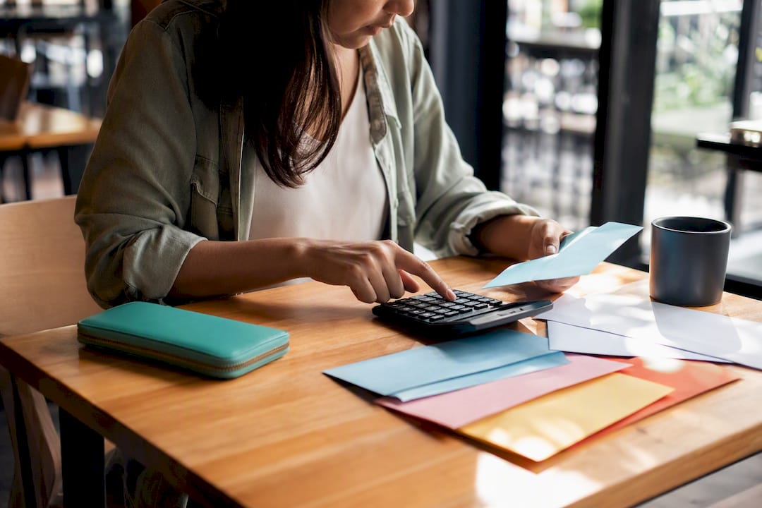 Hands calculating bills with calculator and cash