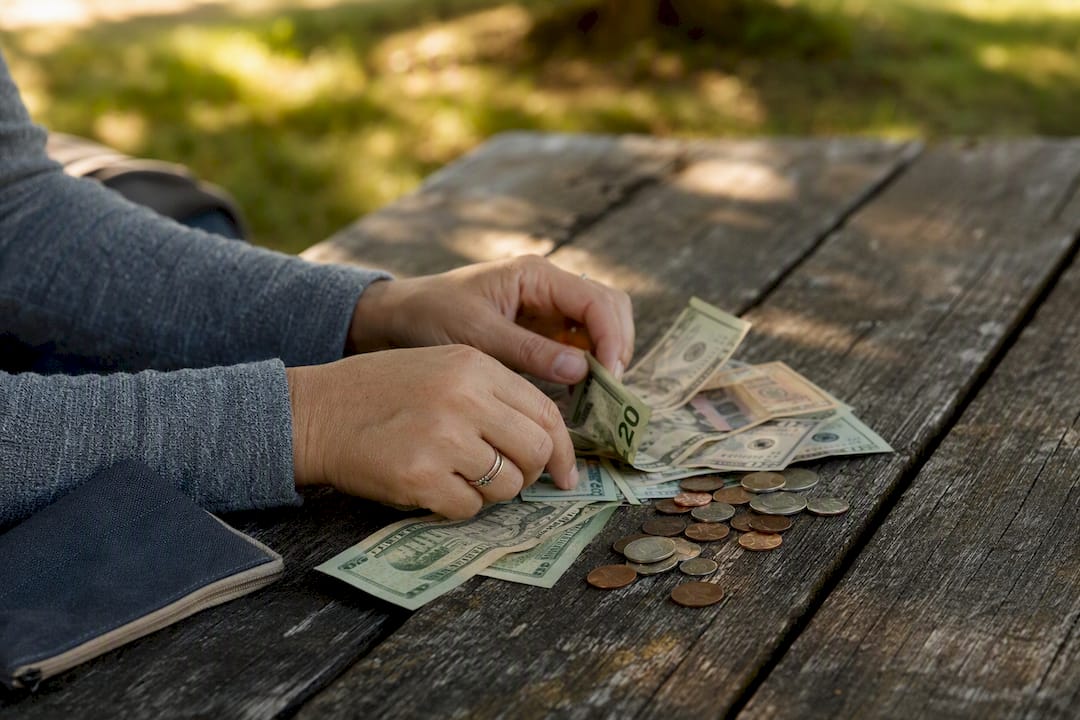 Hands sorting cash and coins on kitchen table